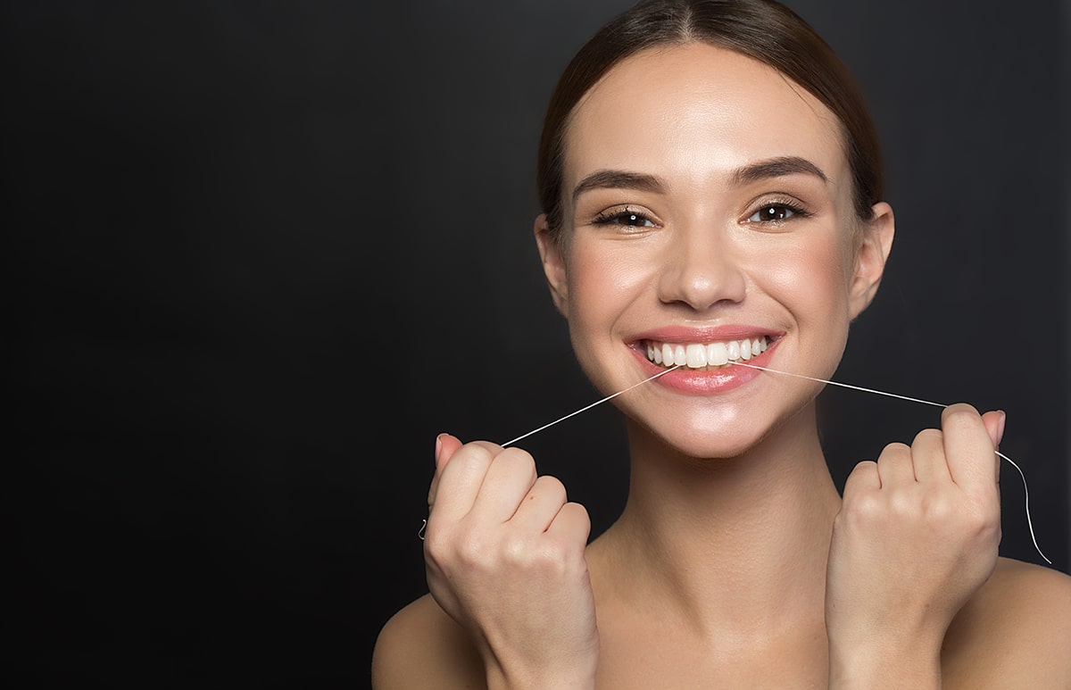 woman smiles with floss after answering the question how often should i floss