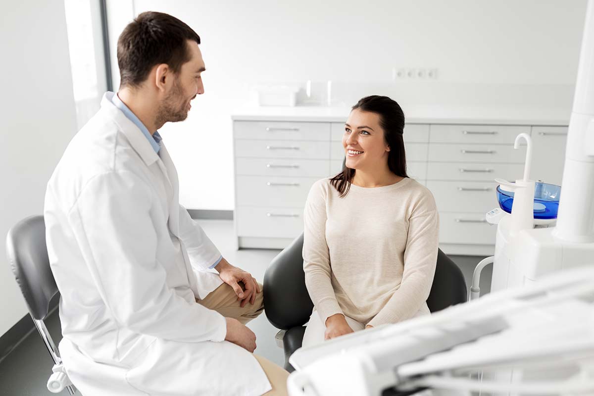 dentist consulting with smiling woman in an effort for choosing your dental practice
