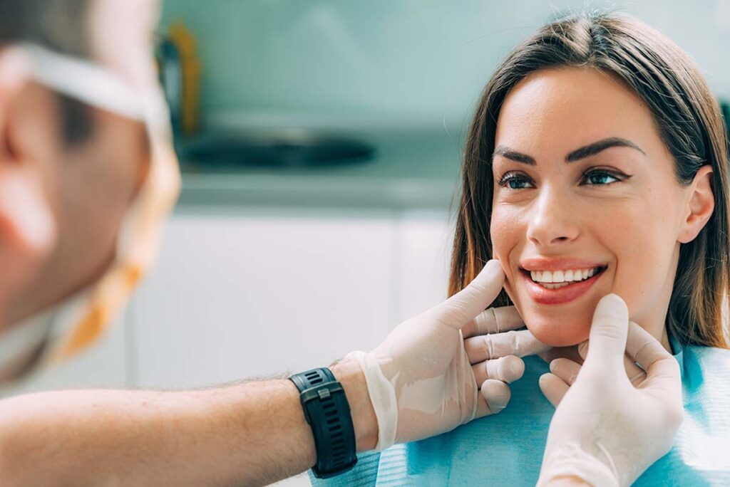 dentist examining woman's smile as he answers, what are cosmetic dental services