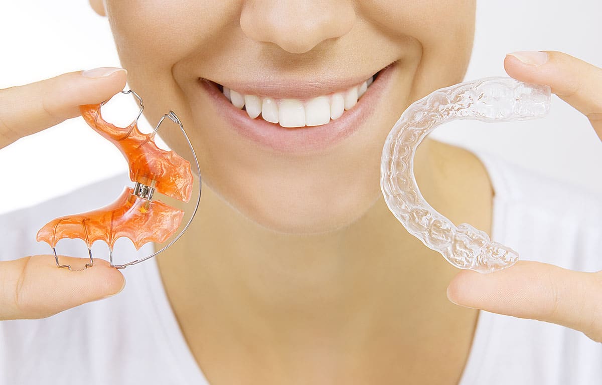 a woman holding retainers as she looks for how to prevent teeth shifting