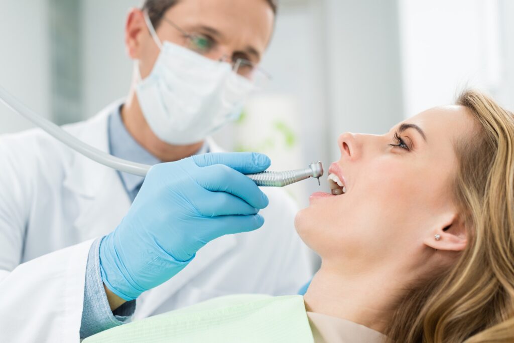 Female patient at dental procedure using dental drill in modern dental clinic