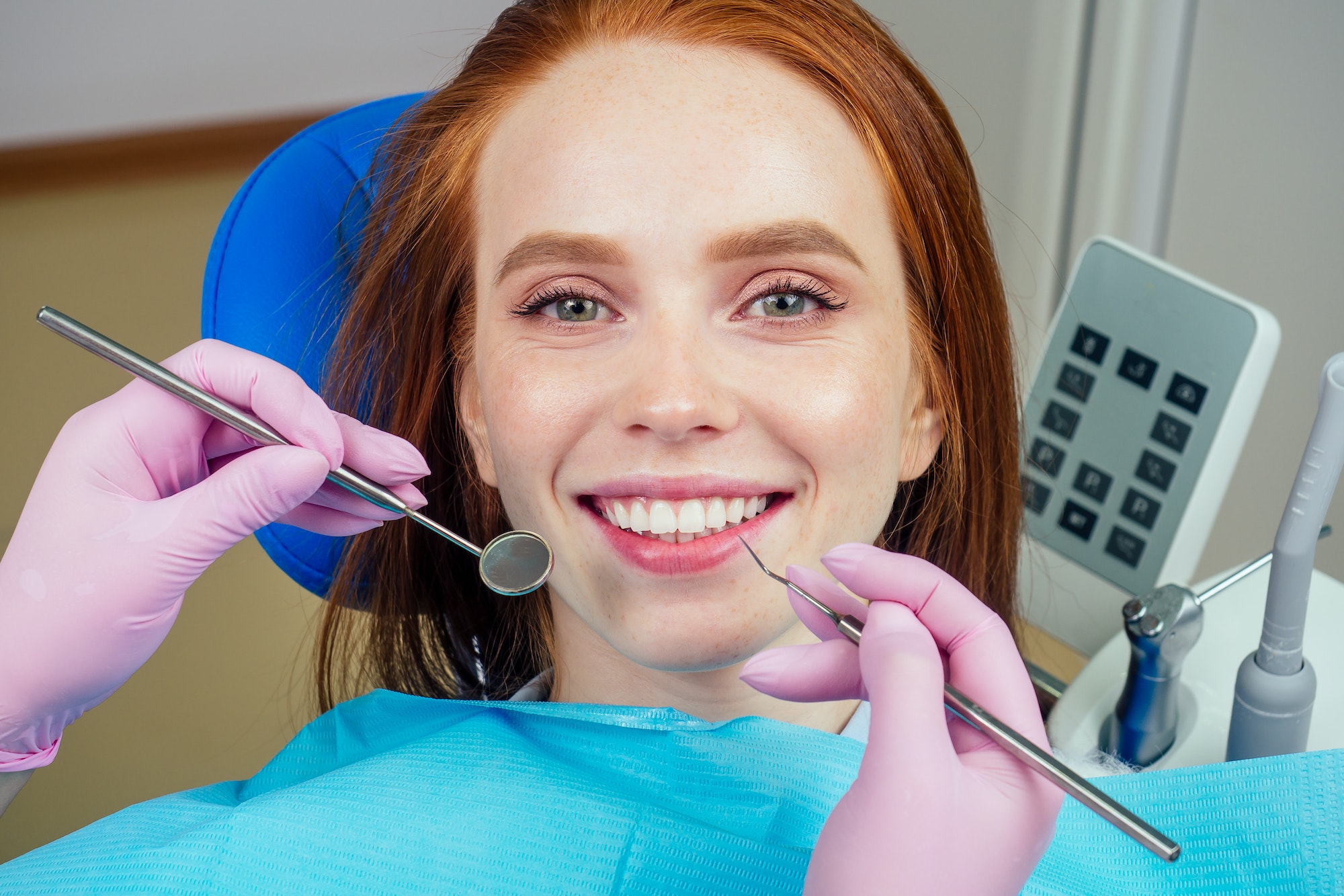 Portrait of an attractive smiling redhaired ginger customer girl in a dental chair